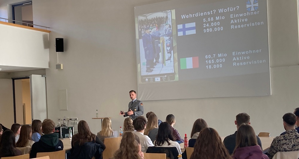 Junger Mann in Uniform vor einer Leinwand im Klassenraum
